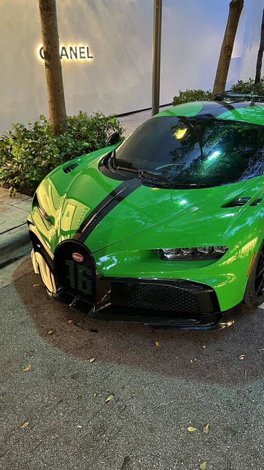 A bright green Bugatti Chiron Pur Sport supercar parked on a street with a 'CHANEL' storefront visible in the background.