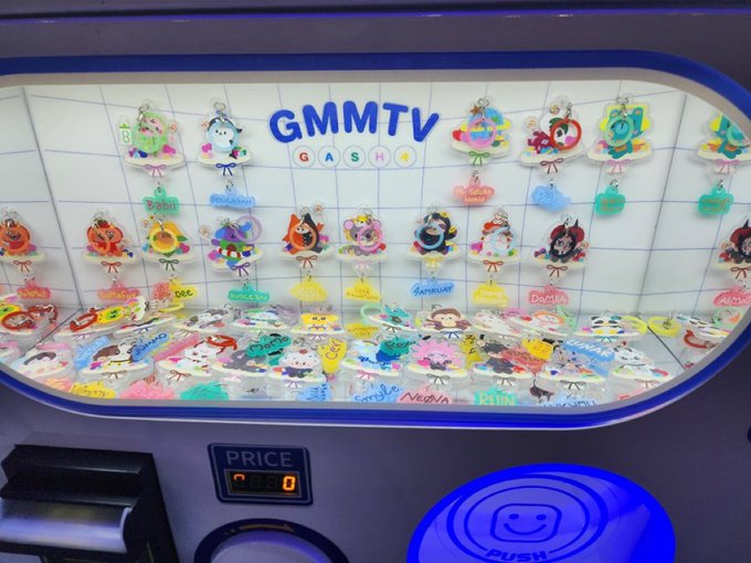 A GMMTV Gasha vending machine displays colorful character keychains with names like "Dome," "Gulf," "Dew," "Mix," "Pepper," "Gun," and "Tulip" alongside a blue "PUSH" button and a digital price counter, matching the fan's request for a "Dometir" spin at the GMMTVFANIVAL2026 event.