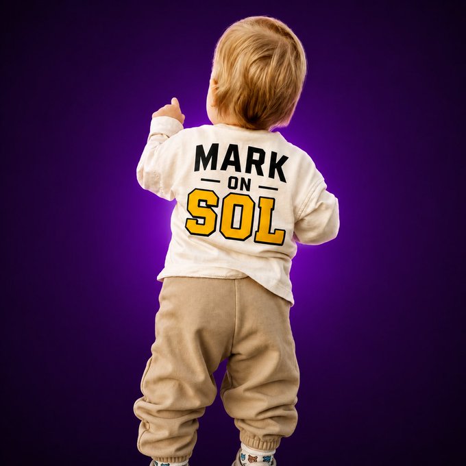 A young child with blonde hair is photographed from behind against a purple background, wearing a white shirt that reads "MARK ON SOL" in black and yellow lettering.