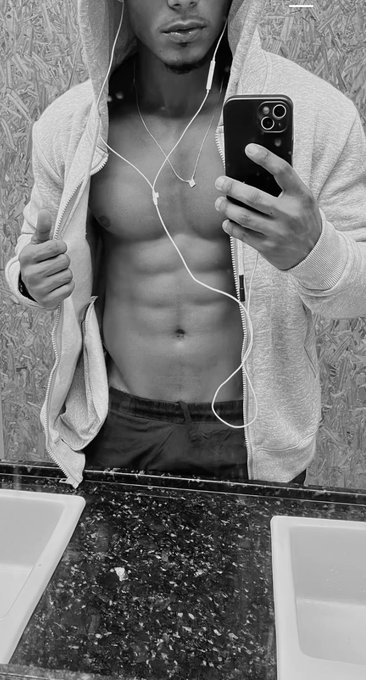 A black-and-white mirror selfie shows a shirtless man in a gray hoodie pulling open the zipper to reveal his abs, while holding a smartphone and wearing earphones in front of a marble double-sink countertop. The image appears to be promotional content from a linkpriv.com page, likely used as a teaser to drive traffic to the linked site.