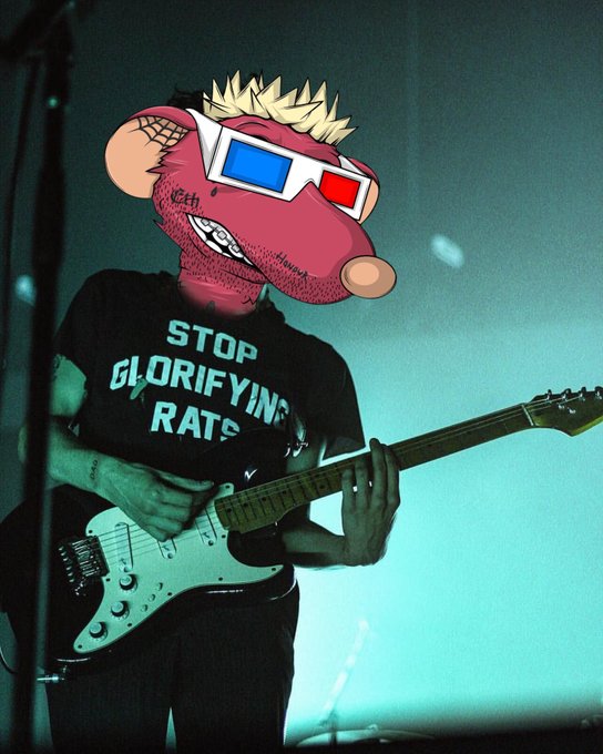 A concert photo of a guitarist wearing a 'STOP GLORIFYING RATS' t-shirt, with their face obscured by a cartoon rat head wearing 3D glasses.