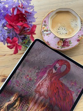 A flat-lay photograph showing a tablet displaying an artistic image of a red flamingo, positioned next to a cup of espresso on a floral saucer and a bouquet of red and purple flowers on a wooden surface.