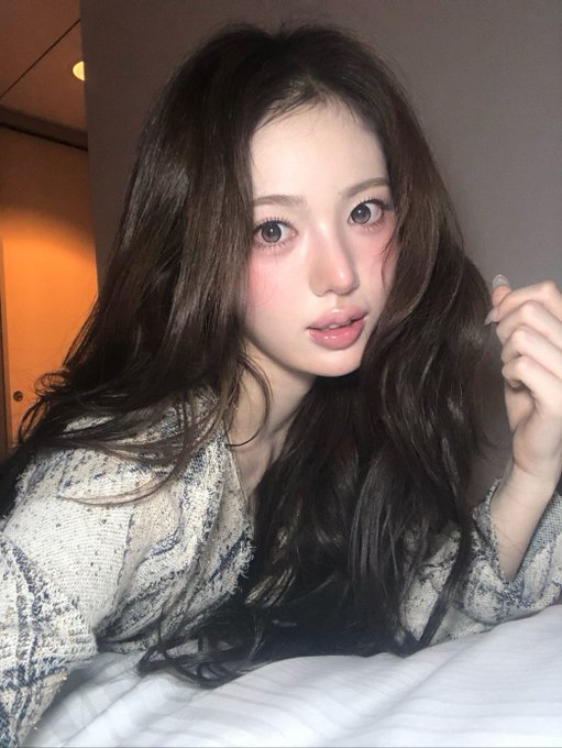 A young woman with long wavy brown hair poses for a close-up selfie, featuring soft glam makeup with flushed cheeks and glossy lips, wearing a textured cream and navy patterned sweater. The image, tagged with "#Sui" and the date "260927," appears to be a casual personal photo shared under the username "bubble."