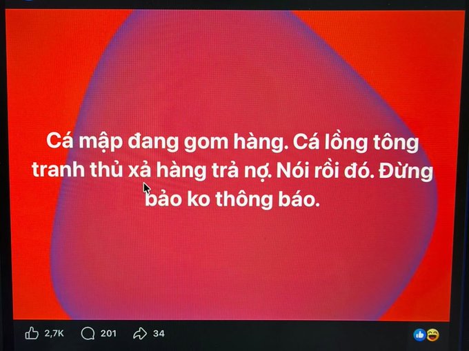 Social media post with red background and Vietnamese text reading 'Cá mập đang gom hàng. Cá lòng tòng tranh thủ xả hàng trả nợ. Nói rồi đó. Đừng bảo ko thông báo.' with 2.7K likes.