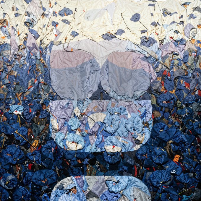 A mixed-media artwork depicts a skull emerging from a textured surface composed of blue and white plastic-like materials.