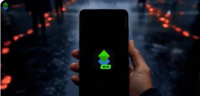 A hand holding a smartphone displaying an app icon with green and blue arrows and 'BETA' label, set against a dark urban background with red glowing lights.