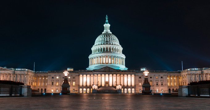 The U.S. Capitol building illuminated at night with its iconic dome and columns lit up against a dark sky.