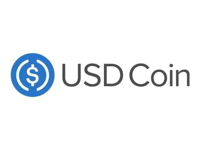 The logo for USD Coin (USDC), a cryptocurrency, displays a blue circular icon with a dollar sign next to the text "USD Coin" in gray.