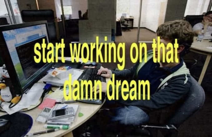 A man works on a computer at a cluttered desk with the motivational yellow text overlay 'start working on that damn dream'.