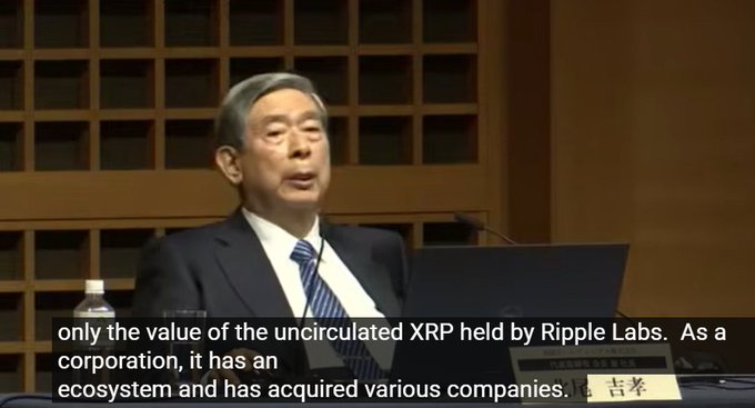 The image features an older man wearing a suit, sitting at a desk with a laptop computer in front of him. He appears to be giving a speech or presentation, possibly discussing the value of the uncirculated XRP held by Ripple Labs. The text in the image reads "Only the value of the uncirculated XRP held by Ripple Labs. As a corporation, it has an acquired various companies." This suggests that Ripple Labs is not only holding onto the uncirculated XRP but also acquiring other companies related to cryptocurrency and blockchain technology.