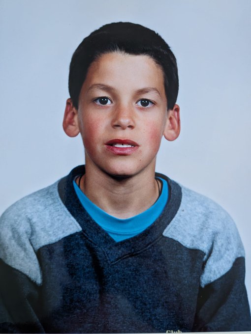 A school portrait photo of a young boy with short dark hair wearing a gray and blue sweater over a blue shirt.