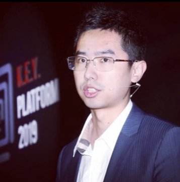 In the image, there is a man wearing glasses, a suit jacket, and a white shirt. He has black hair styled into a spiky look. The man appears confident as he poses for the picture, standing against a black background that features various logos and text such as "Garrett Jin just closed his $ZEC short for an  $11.24M profit". This suggests that the image is related to Garrett Jin's achievement in raising a significant amount of money for a project by using an innovative approach.