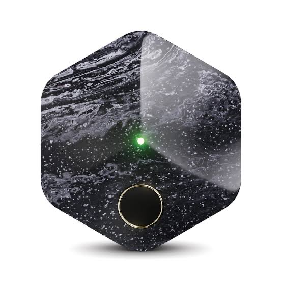 A hexagonal black and white marble-textured device with a glowing green indicator light and a circular button sits against a white background, humorously representing "what happens if I lose my thumbs" as a thumbprint-based smart home or security gadget rendered useless without fingerprint access.