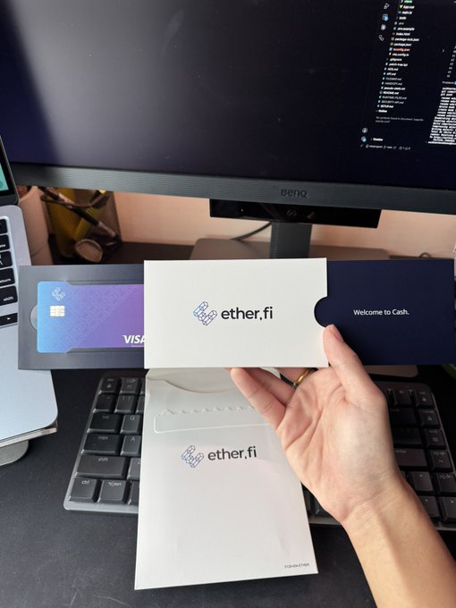 A hand holds an "ether.fi" branded card holder displaying a purple Visa card above a matching "ether.fi" envelope, with the text "Welcome to Cash." visible.