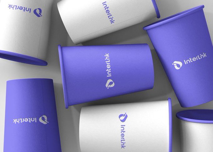 A scattered arrangement of purple and white InterInk branded cylindrical containers or packaging on a gray surface.