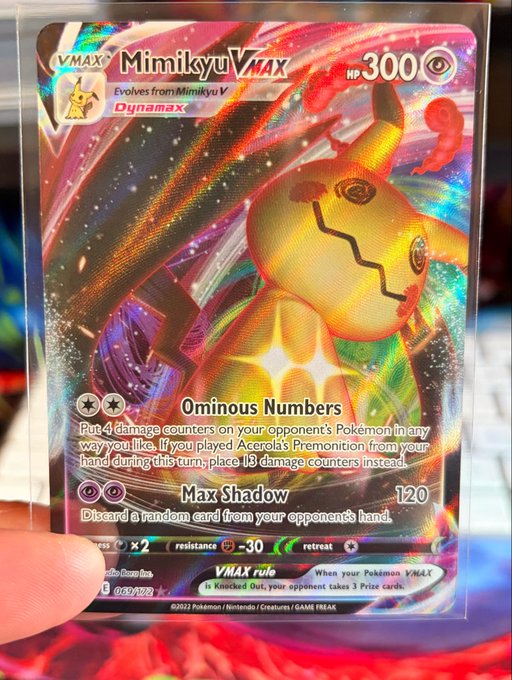 A close-up of a Pokémon Trading Card Game card, specifically the VMAX Mimikyu VMAX card (069/172) from the Dynamax set, showing 300 HP and attacks 'Ominous Numbers' and 'Max Shadow'.