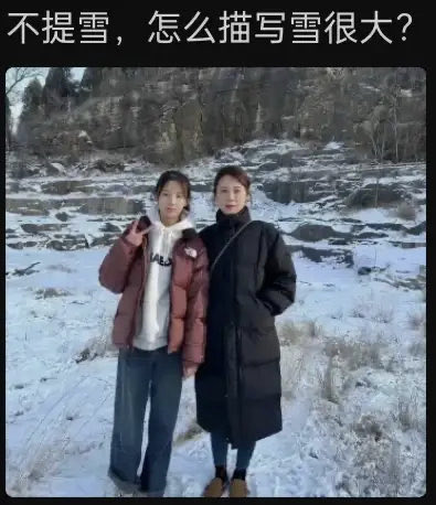 The image features two young women posing in a snowy, rocky outdoor setting, with one wearing a brown puffer jacket and the other in a long black coat, while Chinese text at the top reads "不提雪，怎么描写雪很大？" (How to describe heavy snow without mentioning snow?), highlighting their thick winter attire and the deep snow covering the rugged landscape.