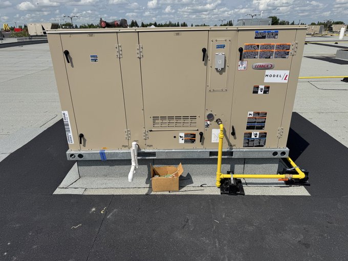 A rooftop HVAC Lennox unit (labeled 'MODEL X') installed on a commercial building rooftop with yellow gas piping and warning labels visible on the equipment.
