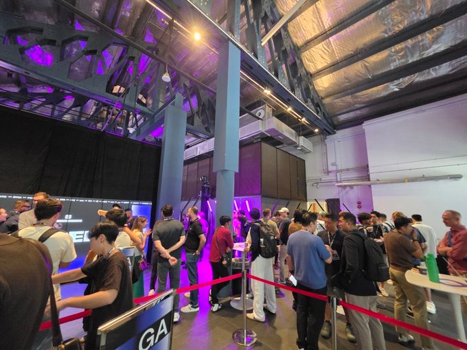 A bustling crowd of attendees gathers in a vibrant, purple-lit event hall, with partial text "GA" visible on signage, capturing the energetic atmosphere of Token2049's first day focused on RWA, tokenized stocks, structured products, AI, and crypto institutionalization.