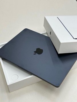 A dark blue Apple MacBook laptop rests on its white packaging box.