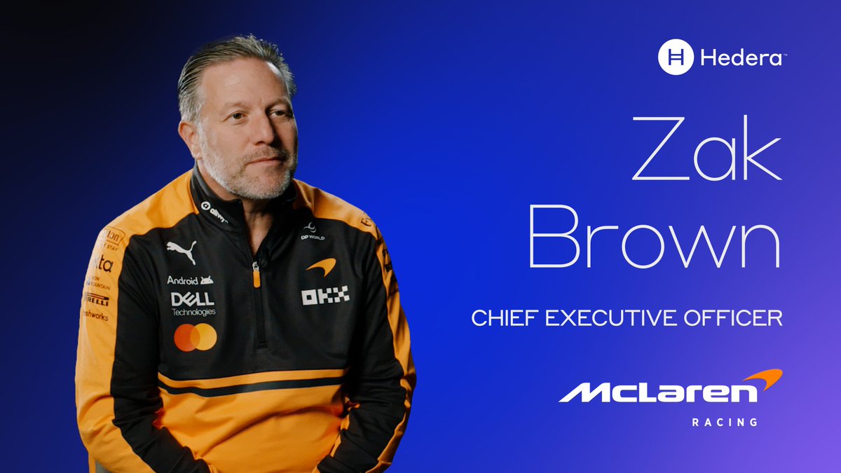 The image features a man wearing an orange and black jacket with the word "McLAREN" written across his chest. The man appears to be smiling, possibly posing for a photo or video. The background of the image has a blue hue that contrasts with the man's attire. Below the man, there is text that reads "@zbrownCEO", which might indicate that he is the CEO of McLaren Racing. This could imply that he is involved in innovation and partnerships within the racing industry, as well as being an advocate for collaboration between different organizations or companies.