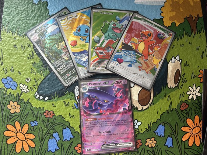 The image features a collection of five Pokemon cards, each with different designs and colors, spread out on a table or surface. One card has a purple background, while another has an orange background. The cards are arranged in various positions, creating a visually appealing display that showcases the diversity of the Pokemon characters depicted.