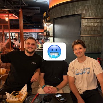 Two men pose at a restaurant table with a third person whose face is covered by a freezing/cold emoji sticker, wearing a white "LOFI" branded t-shirt that aligns with the caption's mention of the $LOFI community gathering in Singapore. The casual meetup setting reflects the post's theme of diverse international holders coming together in support of the Sui Network meme coin.