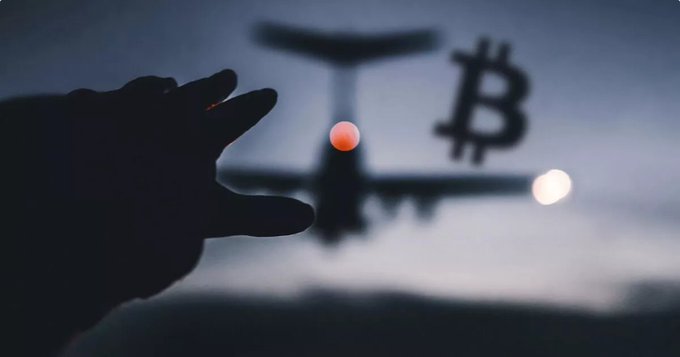A silhouetted hand reaches toward a small airplane in the sky, with a Bitcoin symbol visible to the right of the aircraft.