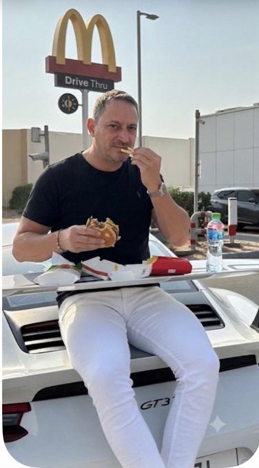 A man in a black t-shirt and white pants sits on the hood of a Porsche GT3, casually eating a McDonald's burger and fries beneath the iconic golden arches and "Drive Thru" sign. The post's caption—"Kriptodan önce" (Before crypto) and "Kriptodan sonra" (After crypto)—humorously suggests his shift from fast food meals to a luxury car lifestyle, implying newfound wealth from cryptocurrency investments.