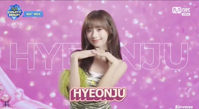 A pink, sparkly promotional image from M Countdown on Mnet features UNIS member HYEONJU posing with a heart gesture, with the text "NEXT WEEK" and her name displayed, fitting the post's praise of the group's vibrant visuals.