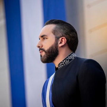 The image features a man wearing a black suit with a blue and white striped collar, standing against a blue background. The man has a beard and appears to be looking off into the distance or at something out of frame. There are also some text elements in the image that read "No matter how Bitcoin moves.. El Salvador keeps buying. This is real conviction."