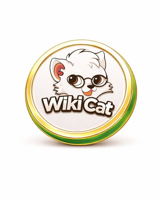 The image features a white cat with glasses wearing a gold hat that says "WIKI CAT" on it. The cat appears to be looking directly at the camera, giving off an impression of curiosity or playfulness. The background of the image is plain and white, which helps draw attention to the cat and its hat.