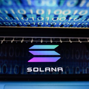 A laptop displaying the "SOLANA" logo with its stacked gradient symbol sits in front of a screen showing binary code, visually representing the blockchain technology behind the post's news about Solana's global expansion into Mexican payments, Hong Kong ETFs, and Vietnamese startups.