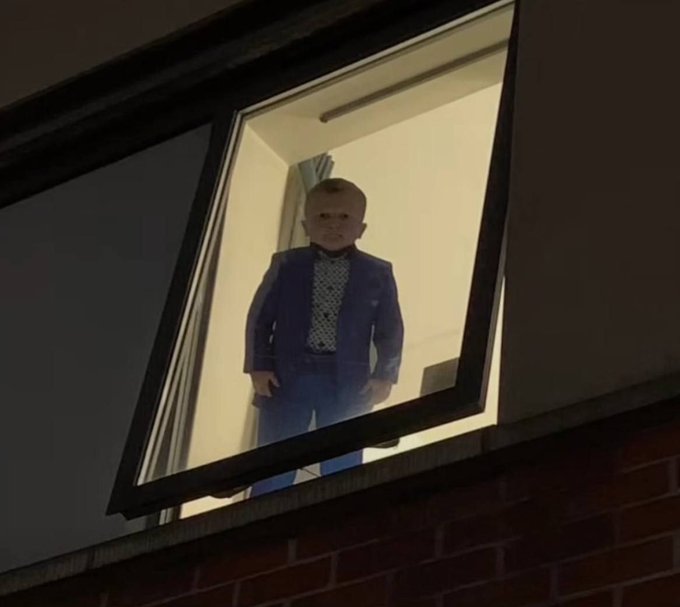 A young boy dressed in a blue suit stands in a window frame, looking out at the viewer. This image humorously relates to the accompanying post by depicting a persona who might be unimpressed by a wedding, opting instead for investments in cryptocurrency.
