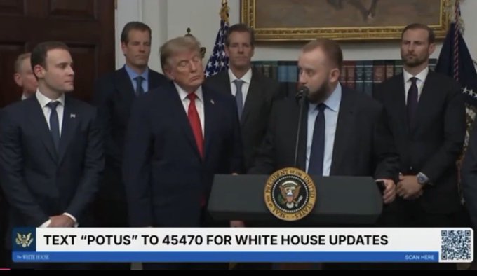 A press briefing featuring Donald Trump standing alongside several officials, including a bearded man at a podium displaying the Presidential Seal, with an on-screen banner reading "TEXT 'POTUS' TO 45470 FOR WHITE HOUSE UPDATES." The image relates to the post's reference to $LINK (Chainlink) by humorously connecting the official presidential setting to crypto culture, suggesting that blockchain figures have reached mainstream political prominence.