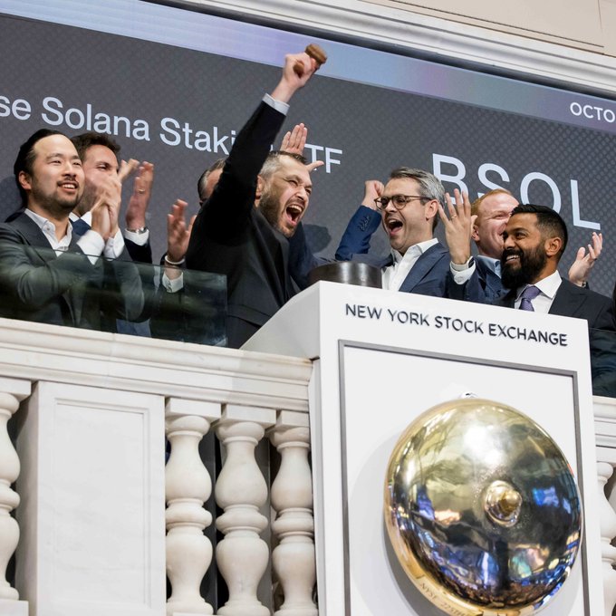 The image shows a group of people gathered around a booth with a bull's eye charm, which could be a coin or a trophy related to stockbroking success. A person dressed as a bulls-eye appears to have just thrown up his arms in victory, indicating that he has won some sort of contest or achieved significant financial gains. The crowd of onlookers is celebrating this achievement and sharing the moment together. This scene represents the theme "Back to Work", implying that these individuals are partaking in an event related to stockbroking or financial markets.