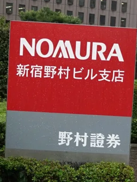 A large red and gray sign displays "NOMURA" in English along with Japanese text reading "新宿野村ビル支店" (Shinjuku Nomura Building Branch) and "野村證券" (Nomura Securities), marking a Nomura Securities office location. The image visually supports the headline about the $420B Nomura receiving Japan's first new crypto license in four years, highlighting the company's presence in Japan's financial sector as it expands into cryptocurrency services.