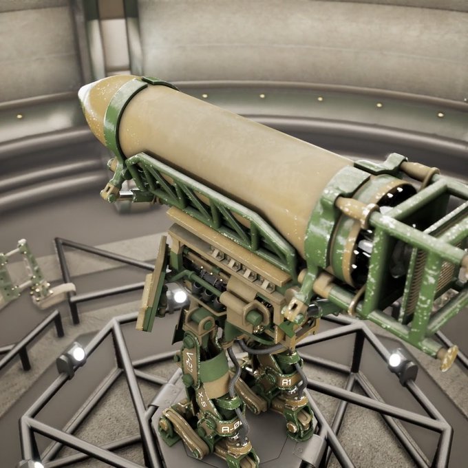 A 3D render of a large, olive-green mechanical turret or weapon mounted on bipedal legs, positioned in an industrial-looking room with spotlights.