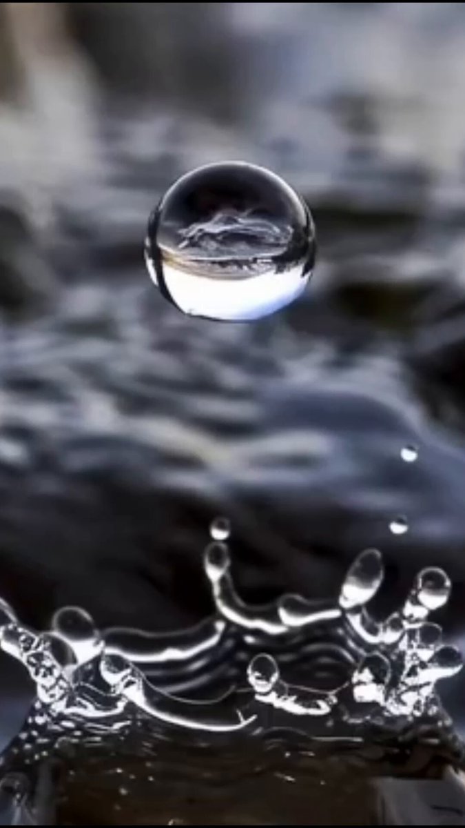 The image features a water droplet falling from the sky onto a rock or surface below. The droplet creates a small splash as it hits the surface, with several smaller droplets scattered around the main one. This scene can be related to the concept of consistency and how small daily actions can lead to meaningful results over time. Just like the droplets gradually wear away the stone, consistent efforts in various aspects of life can accumulate and create significant change or improvement. The image serves as a reminder that even seemingly small actions can have a big impact when performed consistently.