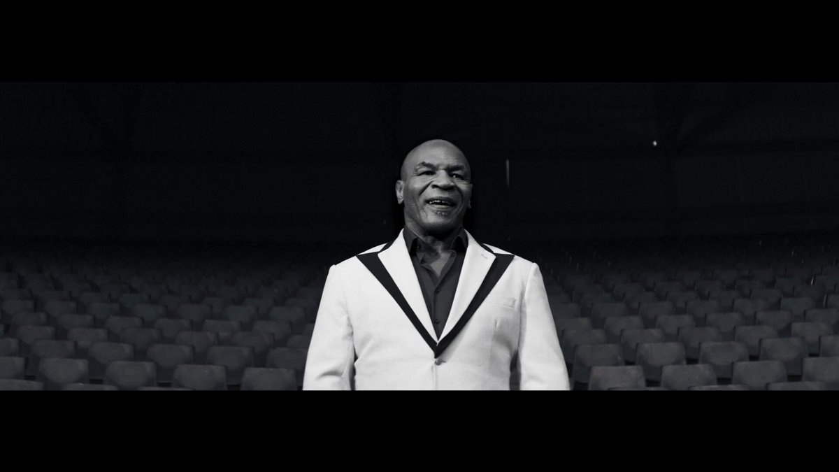 The image features a man wearing a white suit standing in front of an empty stadium filled with rows of chairs. The man appears to be posing for a photo or recording a video, possibly related to sports events like the World Cup. The focus on the man's attire and the empty stadium suggests that he is involved in some form of marketing or promotion related to the event. This could include promoting a player, discussing transfer opportunities, or highlighting any controversies surrounding the event. The post emphasizes the idea that anyone can create markets by capturing interesting moments from sports events like the World Cup.