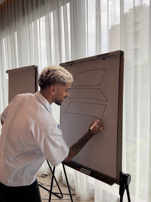 A blonde man in a white shirt attempts to draw a Solana logo on a whiteboard, but the result resembles a poorly rendered, blocky 'S' shape with jagged edges. The caption playfully invites viewers to challenge the attempt by sharing their own worse drawings in the comments.