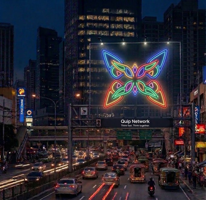 A nighttime city street scene featuring a large, colorful neon butterfly sign above traffic. Text on the sign reads 'Quip Network - Think fast. Think together.'