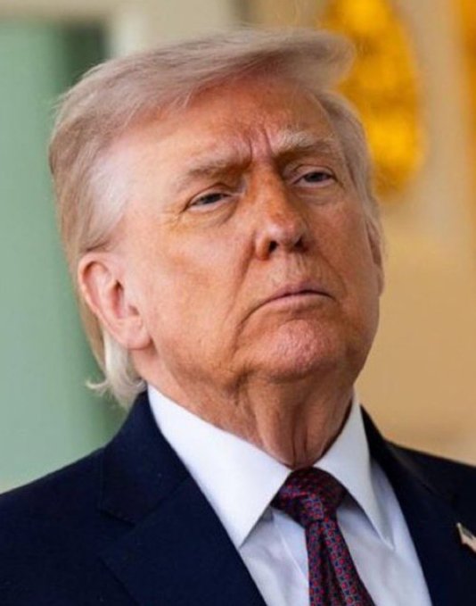 Donald Trump, wearing a navy suit and patterned red tie, looks off to the side with a stern expression during what appears to be a formal address, accompanying a statement about upcoming developments regarding Iran.