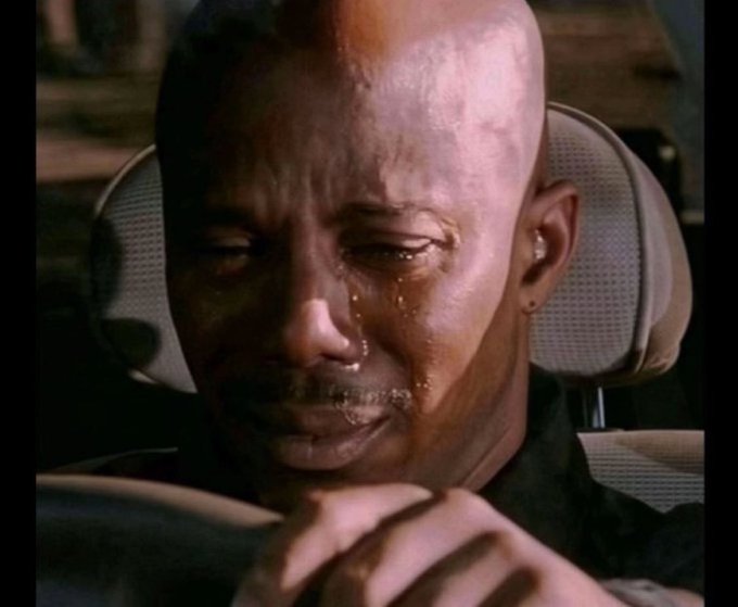 The image shows a close-up of a bald man crying in a car, with visible tears streaming down his face as he grips the steering wheel, capturing a moment of deep emotional distress. The caption suggests this is a slowed-down version of a viral scene, often shared to convey sadness or heartbreak in reaction posts.