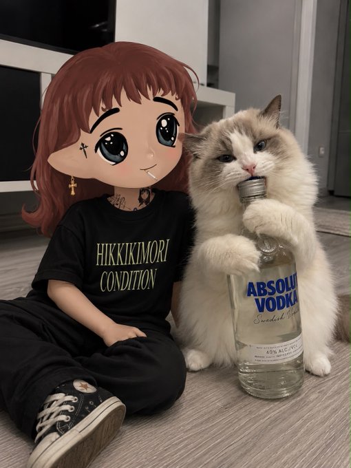 A person wearing a 'HIKKIKIMORI CONDITION' t-shirt with their face covered by an anime-style sticker, sitting next to a ragdoll cat holding an Absolut Vodka bottle.