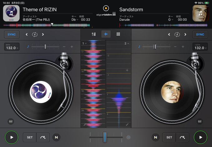 A DJ app interface on a tablet showing two turntables playing "Theme of RIZIN" by The PBJ and "Sandstorm" by Darude, with waveforms and an elapsed time of "00:33".