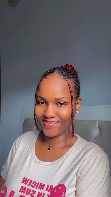 The image features a woman with red hair wearing a white shirt. She has her hair styled into a bun or ponytail, giving her a unique appearance. The background of the photo appears to be a wall, which could potentially be part of an office setting. There is also text in the image that reads "Day 36 of smiling until @ritualnet Mainnet Touch grass today guys, stay cleansed while doing so". This suggests that the woman might be participating in a social media challenge or event related to the #ritualnet hashtag.