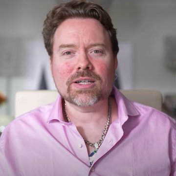 A man with brown hair and a goatee, wearing a pink button-up shirt and a beaded necklace, speaks directly to the camera, likely in a video or interview setting. The image accompanies news of HEX and PulseChain founder Richard Heart's arrest in Istanbul, Turkey, based on an Interpol request from Finland in 2024.