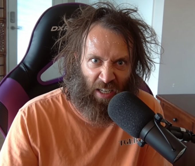 A bearded man with messy hair and an intense expression sits in a gaming chair (branded "DXRacer") speaking intensely into a microphone, wearing an orange shirt with "TGEEZ" visible on it. The image likely depicts the man referenced in the post—the Bitcoin advocate known as "Bitcoin Pleb" or similar—who often debates Bitcoin clients (like Bitcoin Core vs. alternatives) on his podcast, capturing his characteristic heated, passionate demeanor during a rant.