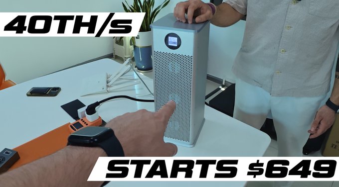 A person points at a silver rectangular electronic device on a table, with bold on-screen text reading '40TH/S' and 'STARTS $649', appearing to be a crypto miner review.